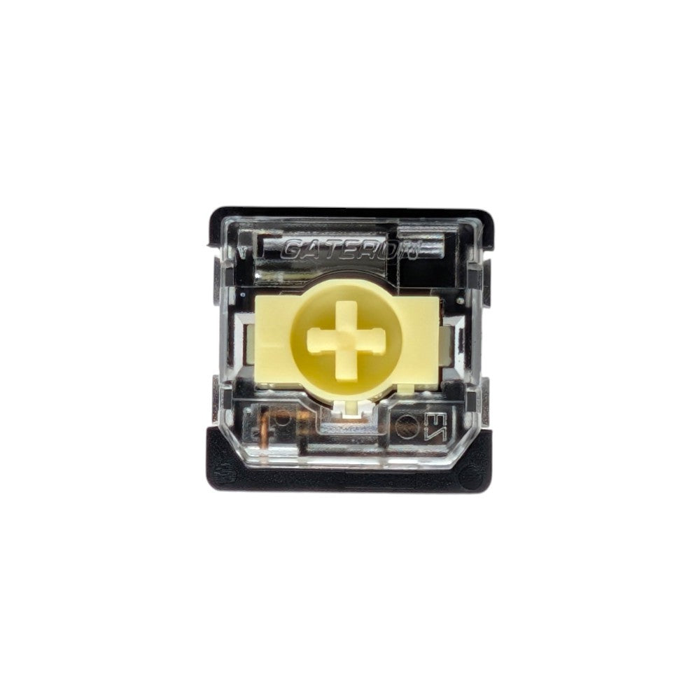 A single Gateron wireless mechanical switch in a top-down view, featuring a black housing, a gold gold-plated contact point with a plus sign, and a clear plastic top cover.