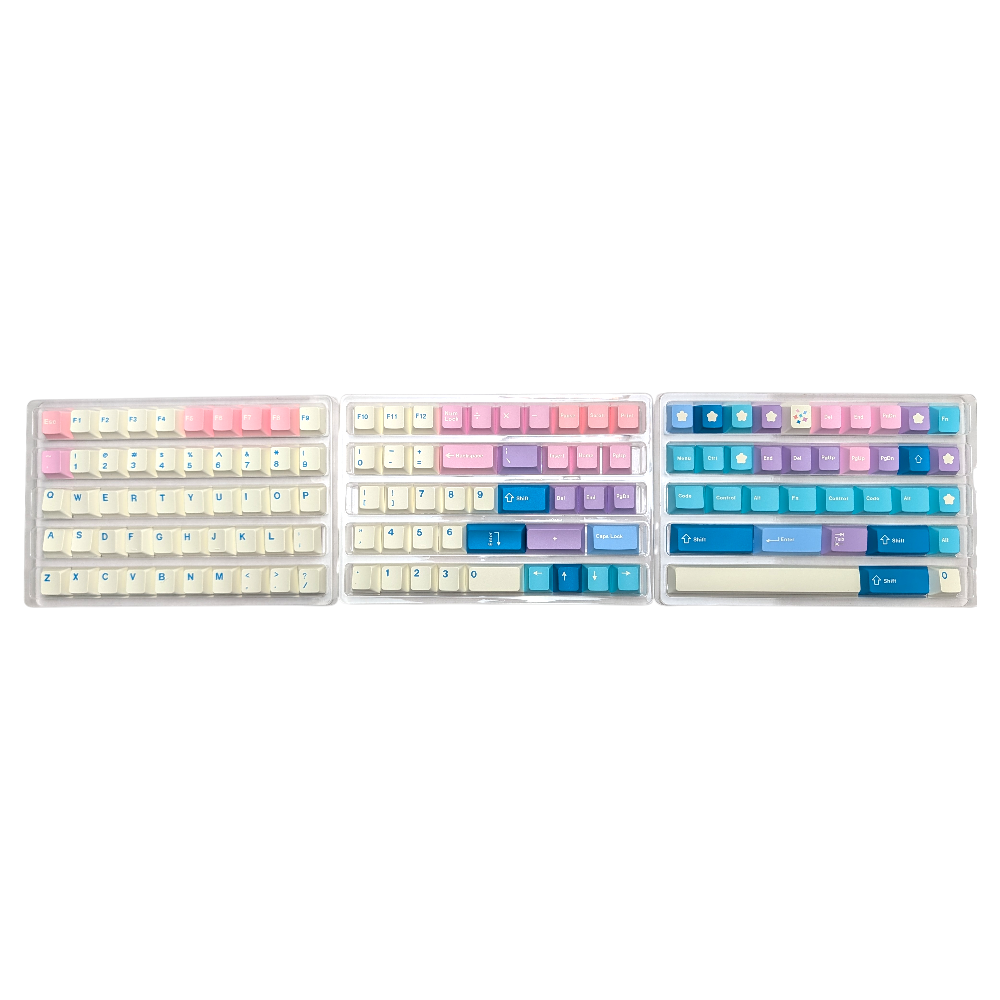 Three trays displaying pastel pink, blue, and cream PBT keycaps in various sizes and layouts.