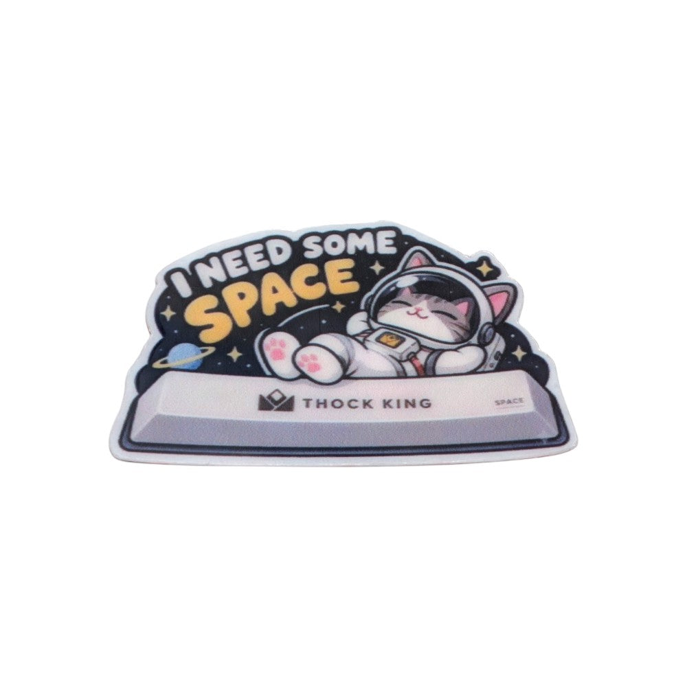 Astronaut cat sticker lounging on a Thock King spacebar, with the words I need some space.