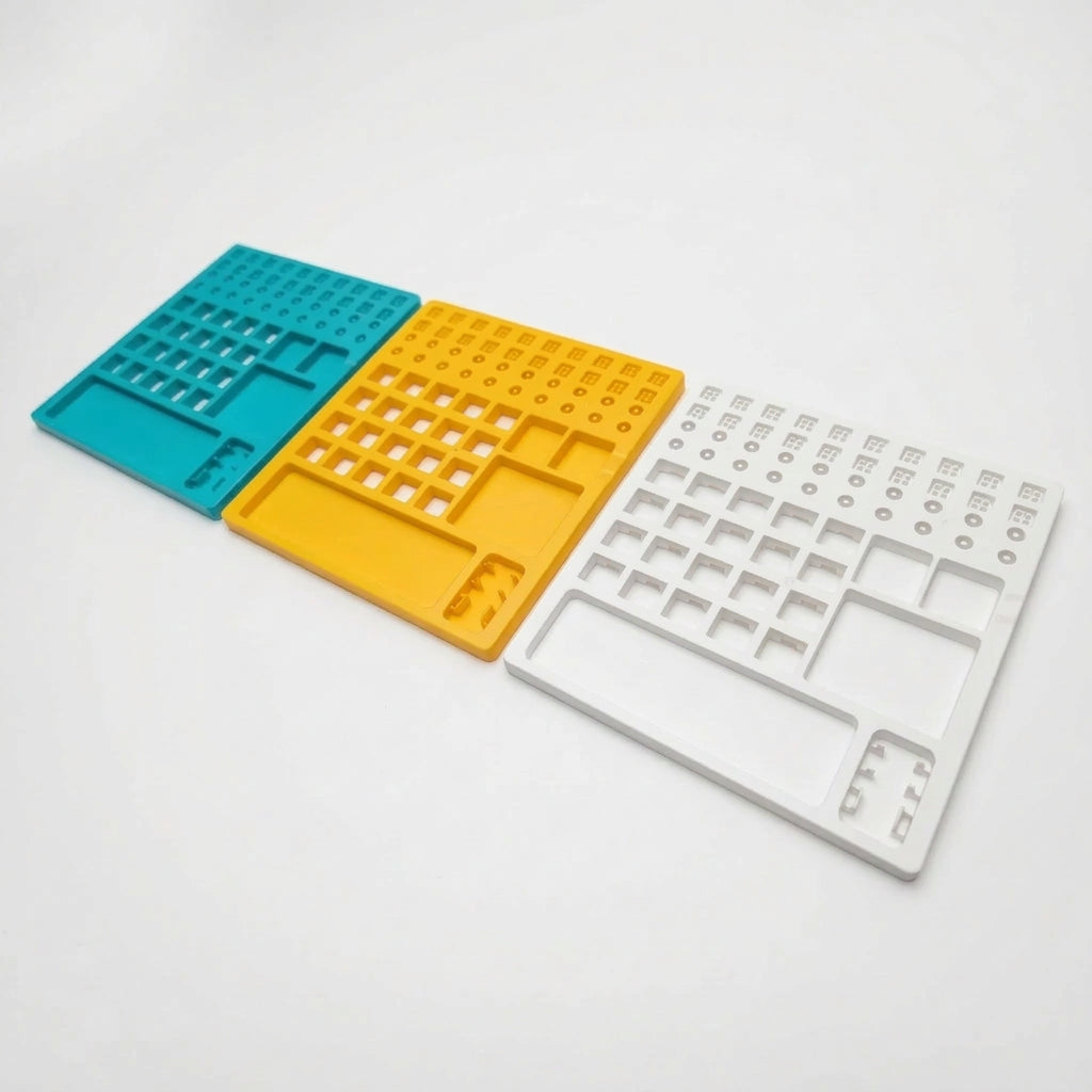 Lineup of all three color options for the plastic switch lube station in teal, yellow, and white.