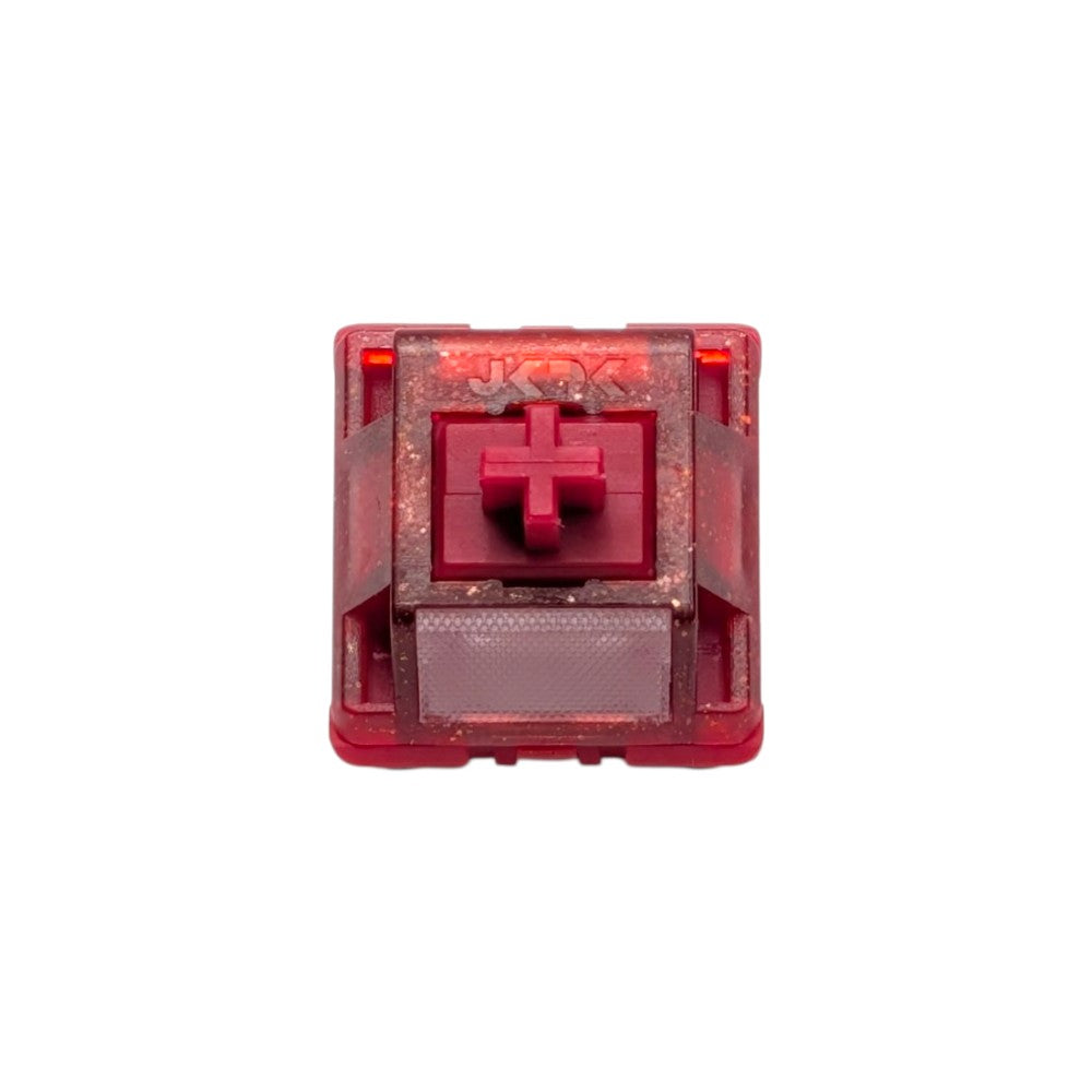 Top-down macro view of the HMX x JKDK Blossom linear switch showing red glitter housing, stem, and light diffuser lens