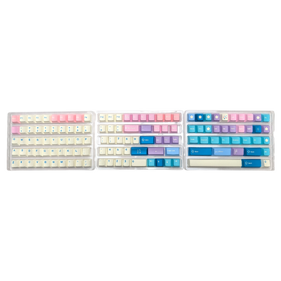 Three trays displaying pastel pink, blue, and cream PBT keycaps in various sizes and layouts.
