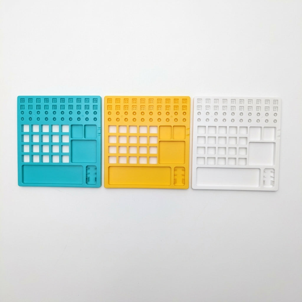 Overhead view comparing teal, yellow, and white plastic mechanical keyboard switch lube stations side by side