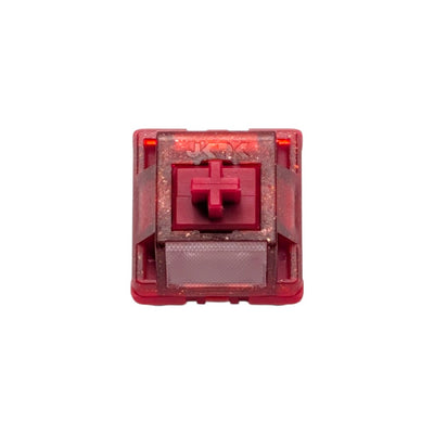 Top-down macro view of the HMX x JKDK Blossom linear switch showing red glitter housing, stem, and light diffuser lens