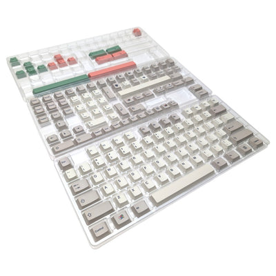A mechanical keyboard keycap set in a clear plastic clamshell packaging, featuring beige, white, gray, green, and red keycaps on a white background.
