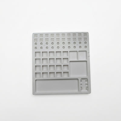 Top-down view of white plastic switch lube station tray featuring stem holders, spring slots, and parts compartments.